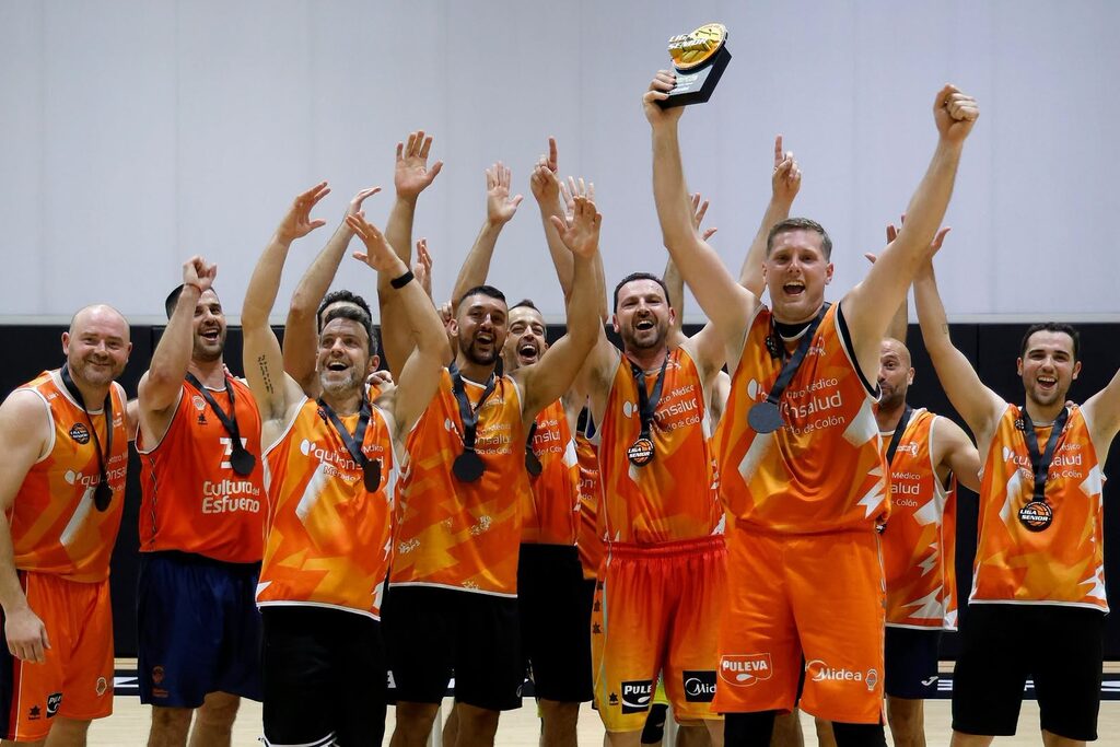 Squadra di pallacanestro che festeggia un titolo con la divisa arancione prodotta da Kauri